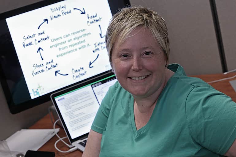 Professor Emilee Rader sitting at her desk. Her computer monitor displays images from her recent research